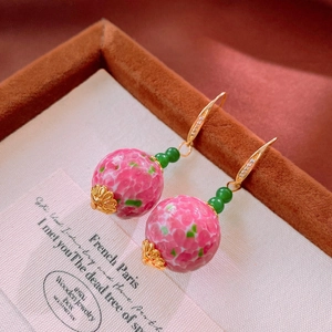 Dettaglio di orecchini vintage con perle di vetro rosa, agata verde e ganci in zircone