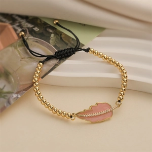 Fashionable gold beaded bracelet with a pink enamel leaf pendant and adjustable black cord
