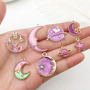 Detailed close-up of purple and gold enamel charms featuring moon, star, and cat motifs