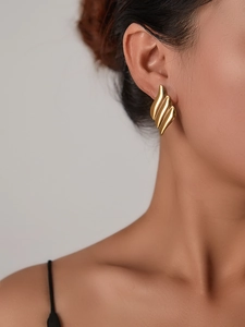 Detail view of 18K gold plated leaf-shaped titanium steel earring on a model