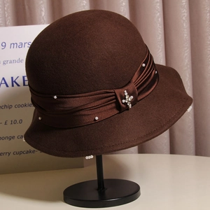 Close-up of brown cloche hat with satin ribbon, pearls and rhinestone brooch detail