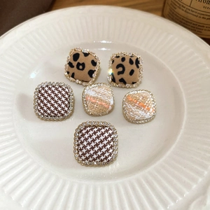 Detail of square fabric stud earrings with leopard and tweed patterns with rhinestones