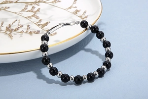 Gros plan du bracelet en perles noires et argentées avec fermoir en métal poli