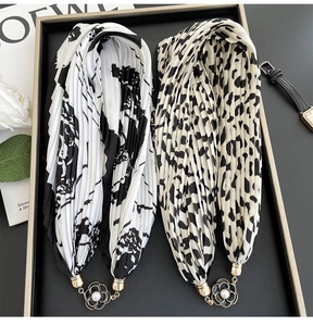 Detail of pleated silk scarves with floral and leopard prints featuring pearl magnetic buckles
