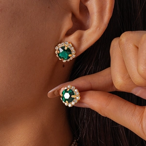 Close-up of vintage emerald green stud earring with diamond halo on golden setting