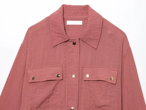 Detail of rose red shirt jacket showing classic lapels and metallic gold buttons