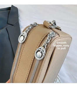 Detail of the smooth double zipper closure and textured leather on the khaki crossbody bag