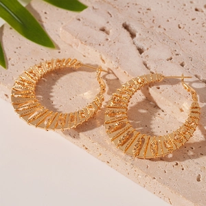 Boucles d'oreilles créoles dorées géométriques avec texture sur socle en pierre