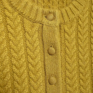 Close-up of mustard yellow cable knit cardigan with matching fabric-covered buttons