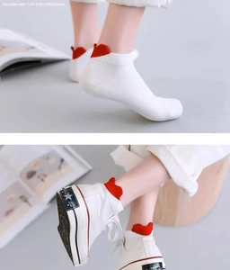White low-cut socks with a red heart heel detail shown on feet and in canvas shoes