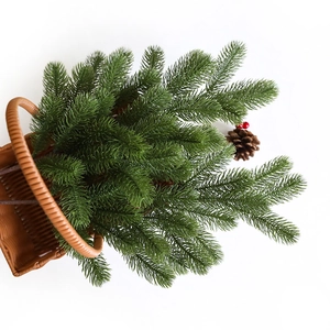 Artificial pine branch with pinecone in a woven basket for Christmas decoration