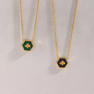 Detail view of hexagonal pendants with green malachite and black resin featuring gold bees