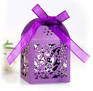 Detailed view of purple laser-cut candy box with heart patterns and satin ribbon bow