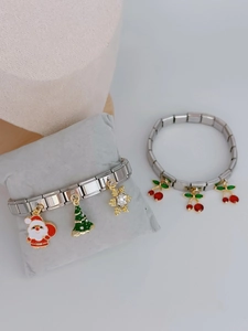 Detail of Italian modular bracelets with cherry and Christmas charms on a velvet pillow