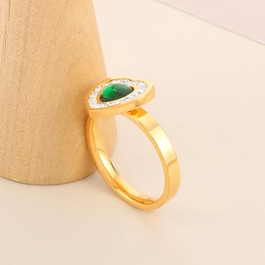 Macro shot of 18k gold heart ring with green gemstone and micro-pave crystals