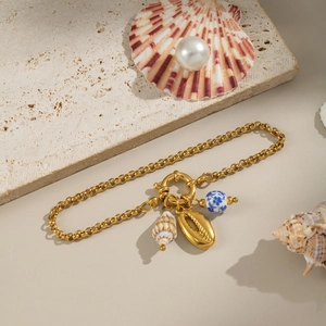 Detailed close-up of golden shell and conch charms on ocean style ceramic beaded bracelet