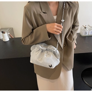 Detailed view of a silver pleated bucket bag featuring 3D butterfly charms and a metal chain