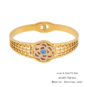 Dettaglio del bracciale rigido in acciaio inossidabile dorato con motivo a fiori e occhio greco