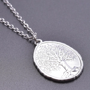 Macro shot of stainless steel oval pendant with detailed tree of life engraving on a chain