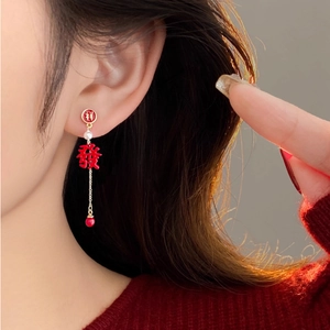 Detail of red Chinese character earring with gold chain and pearl decoration on model