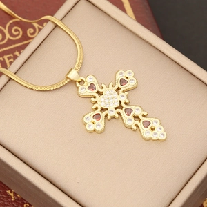 Close-up of 18K gold cross pendant with red heart gems and micro-pave zircons
