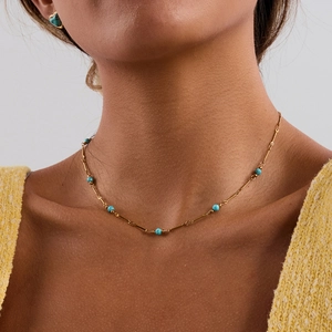 Collier en acier titane doré avec perles turquoise porté par un mannequin au cou