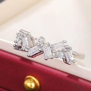Macro detail of silver ring with rectangular zircon stones set against a red jewelry box
