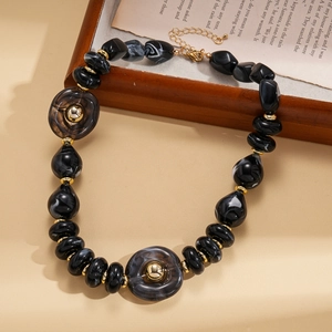 Macro detail of black marble acrylic beads and golden metal rings on long necklace