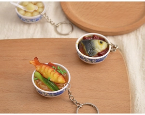 Miniature food keychains with detailed blue and white porcelain bowls on a rustic tray