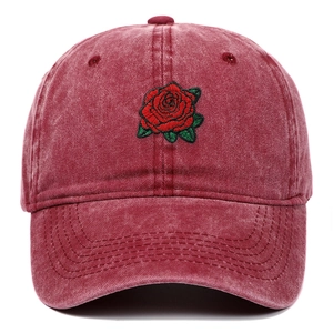 Detalle en primer plano de una gorra de algodón lavado con bordado de rosa roja.