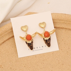 Detail of gold bull skull earrings with red gemstone on a stone display tray