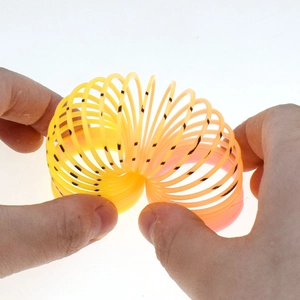 Close-up of hands stretching a mini colorful plastic rainbow spring coil toy