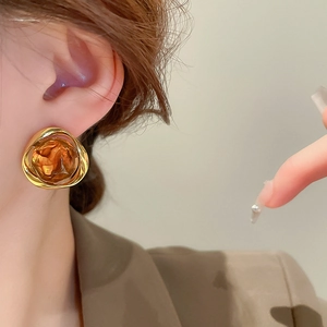 Detail of model wearing geometric gold resin earrings with a vintage amber texture