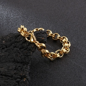Detail of chunky gold O-link chain bracelet with secure lobster clasp on textured surface