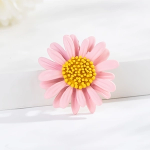 Detailed close-up of a pink daisy brooch with yellow center on white background