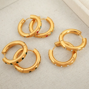 Trois paires de créoles plaquées or 18 carats avec zircons colorés sur tissu beige