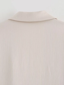 Gros plan du tissu de blazer blanc crème montrant une fine texture verticale froissée