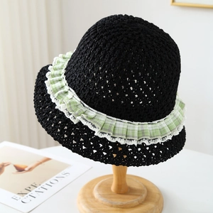 Detailed texture of black crochet straw sun hat with green gingham lace trim detail