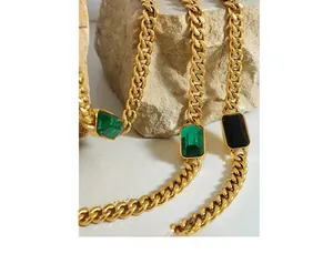 Detailed close-up of gold cuban link chains with emerald-cut green and black stones