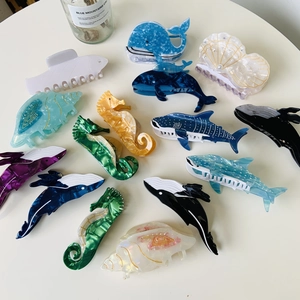 Marine series acetate hair claws featuring whales, dolphins, and seahorses on white desk