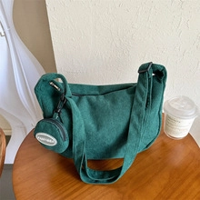 Dettaglio della borsa a tracolla in tela verde scuro con charm rotondo e testo Funnybag