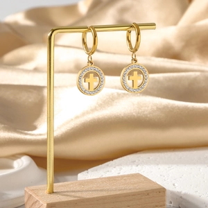 Détail de boucles d'oreilles créoles dorées en acier avec pendentif croix sur support