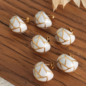 Elegant gold titanium earrings with white marble texture and geometric wire patterns