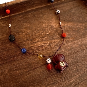 Detailed view of handcrafted wooden pig pendant with ethnic colorful glass beads on a tray