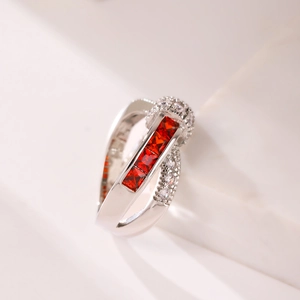 Macro shot of silver ring featuring red rectangular gemstones and sparkling white zircons