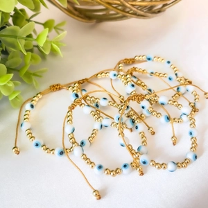 Stack of 18k gold plated evil eye beaded bracelets with adjustable cord strings