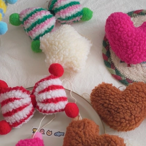 Flat lay of colorful lamb wool plush charms in heart, star, and bow shapes on white fabric