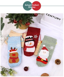 Detailed view of three linen Christmas wine bottle gift bags with festive character icons