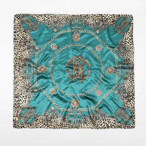 Detailed pattern of leopard print and gold chain motifs on a green silk satin square scarf