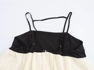 Detail of color block dress featuring thin adjustable straps with metal buckles on black bodice